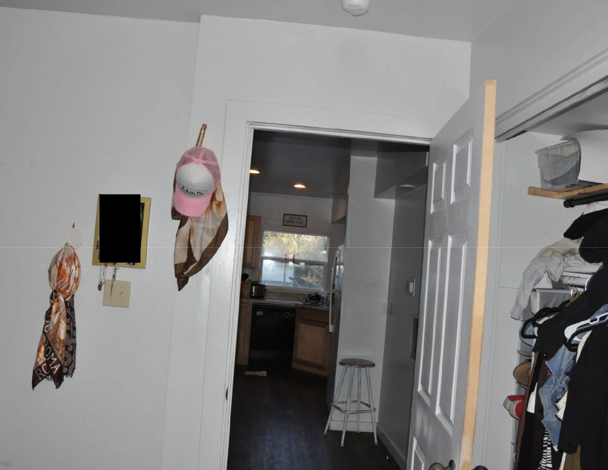 Upper bedroom doorway toward a kitchen, with hanging hats, scarves and an open clothes closet.