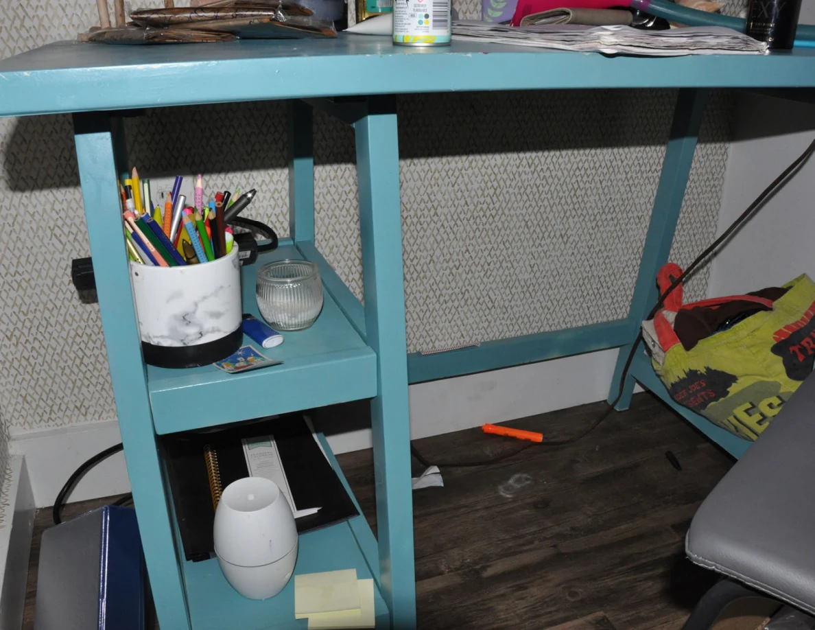 Turquoise desk shelves holding colored pencils, small containers, notebooks and a white oval device.