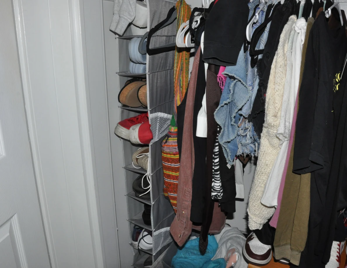 Closet hanging garments beside a vertical fabric shoe organizer.