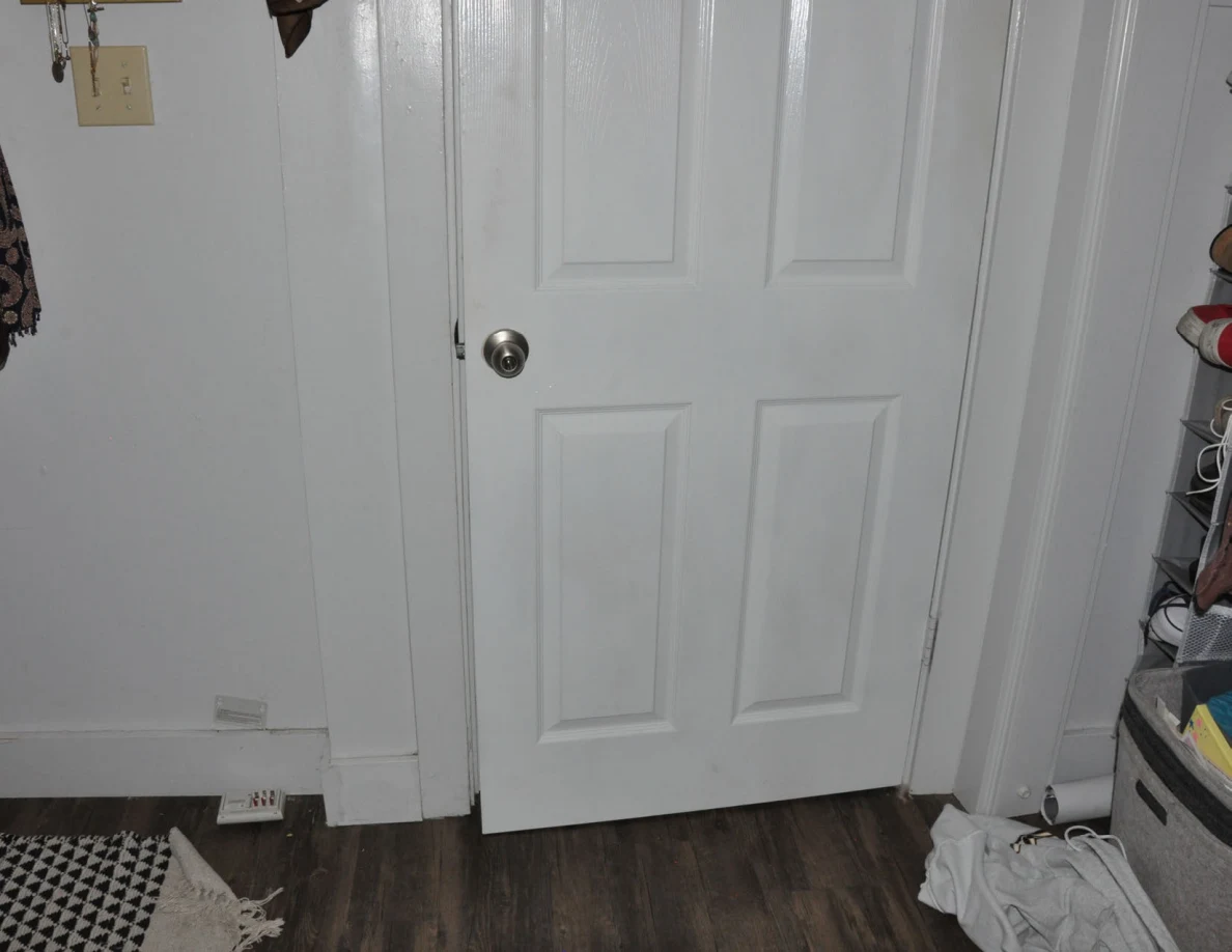 Closed white paneled bedroom door beside the edge of a clothes closet.