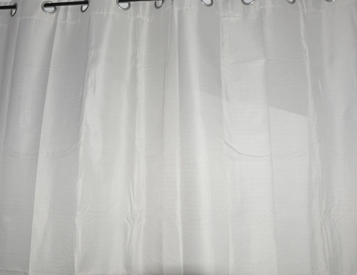 White curtains suspended from a dark rod with metal eyelets.