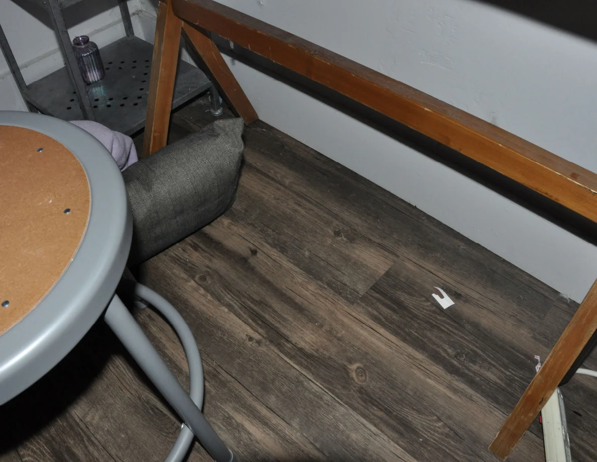 Wood-pattern floor beneath a cosmetics table and stool with a small pale object.