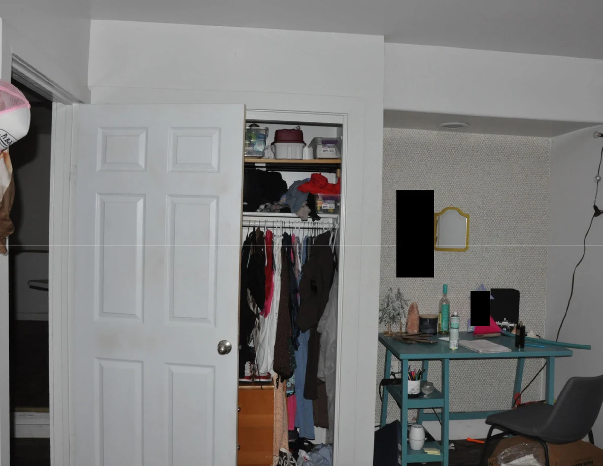 Upper bedroom view of an open closet, turquoise desk and small wall mirrors with redactions.