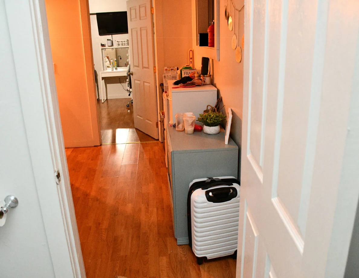 Orange-lit hallway with a white suitcase, small cabinet and objects along the wall.