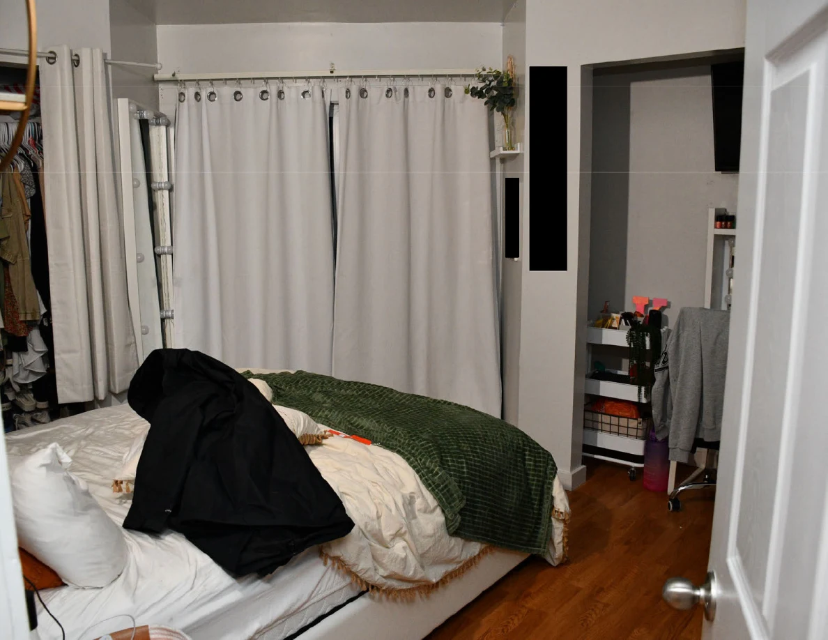 Bedroom with white bedding, green blanket and a large black fabric bag laid across the bed.