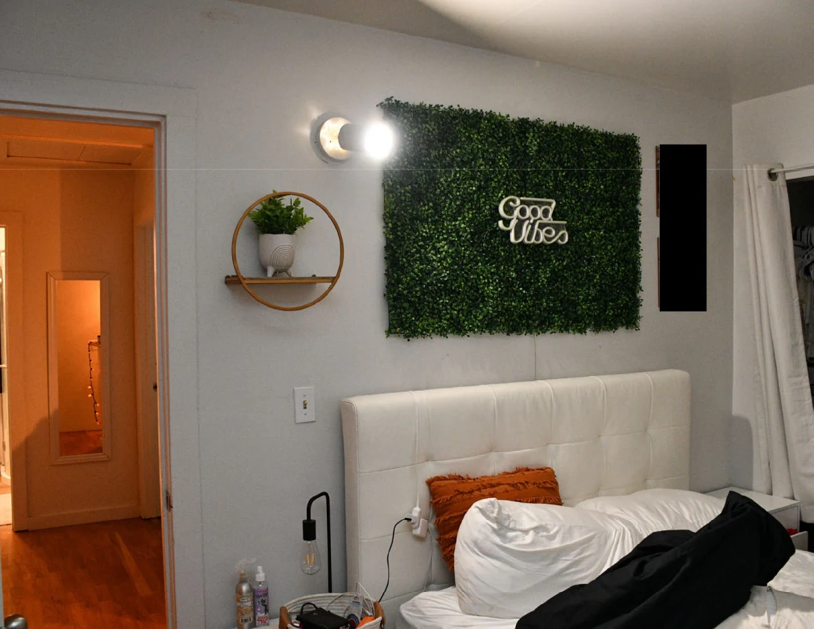 Good Vibes greenery panel above a white bed headboard, wall planter and lamp.