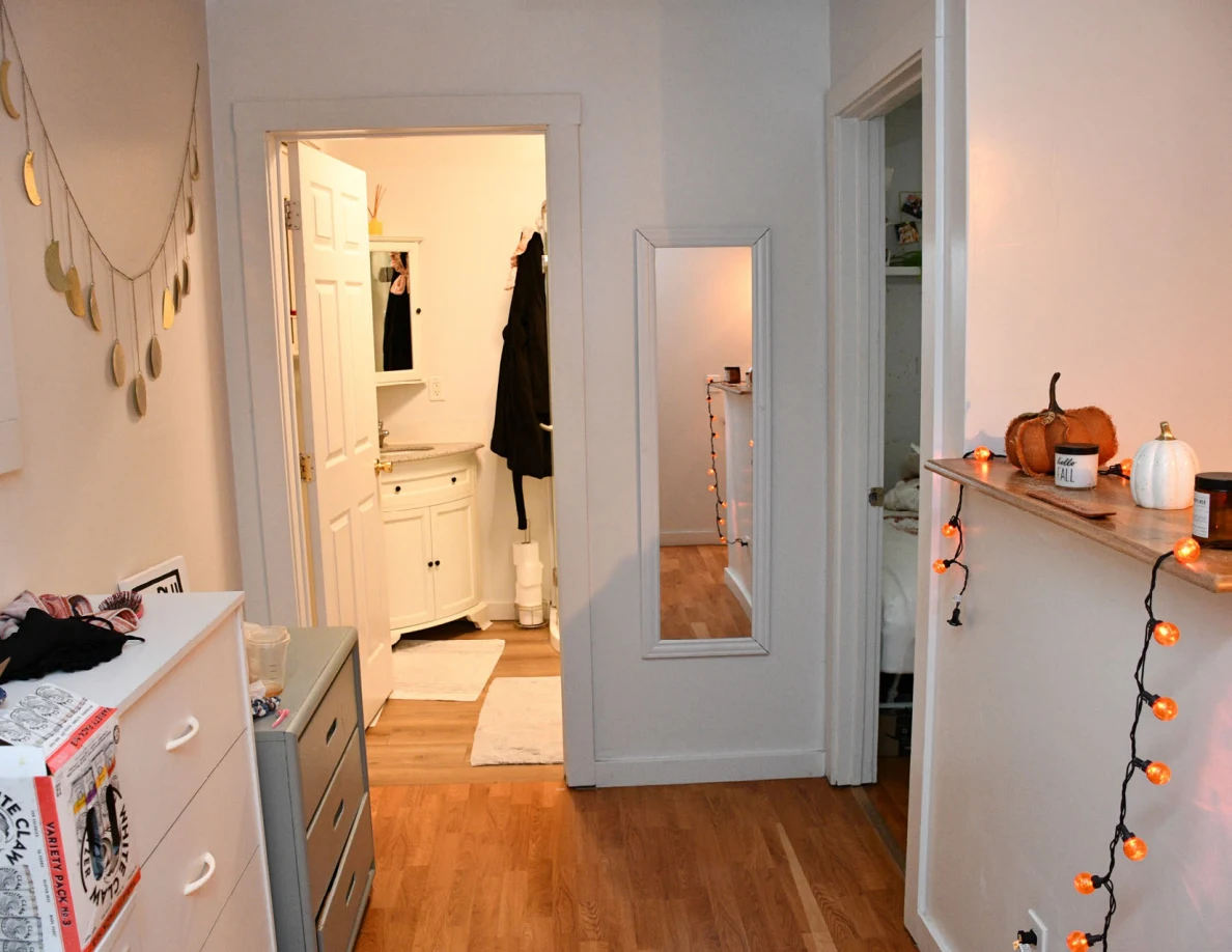 Hallway with cabinets, moon decorations and pumpkin string lights leading to a bathroom vanity.