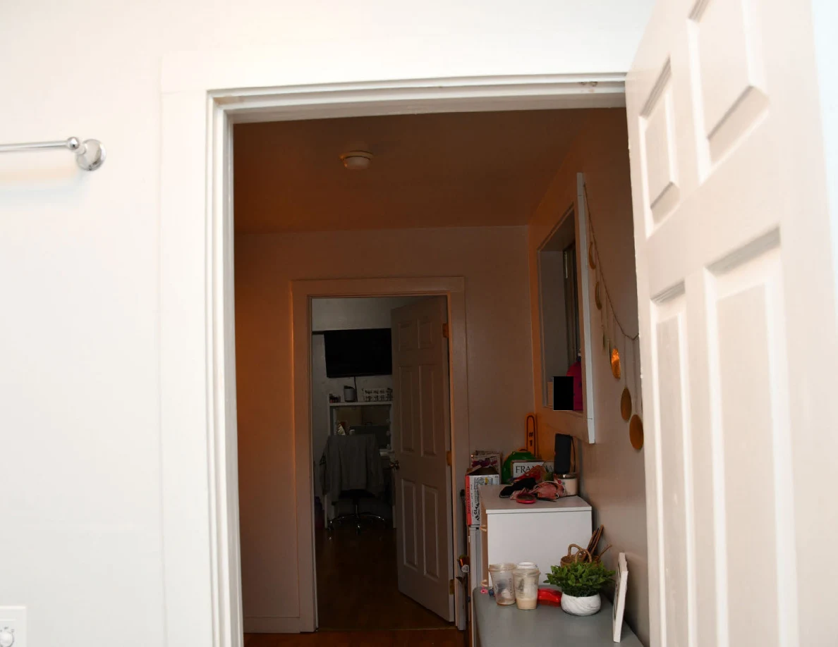 Upper bathroom doorway looking down a hallway toward a vanity and television.