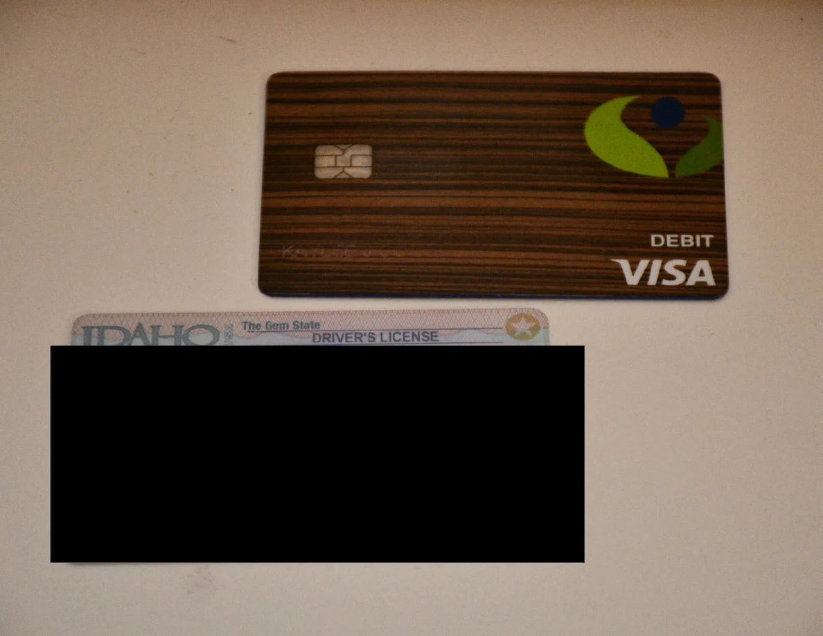 Closer view of a bank card above a redacted Idaho identification card.