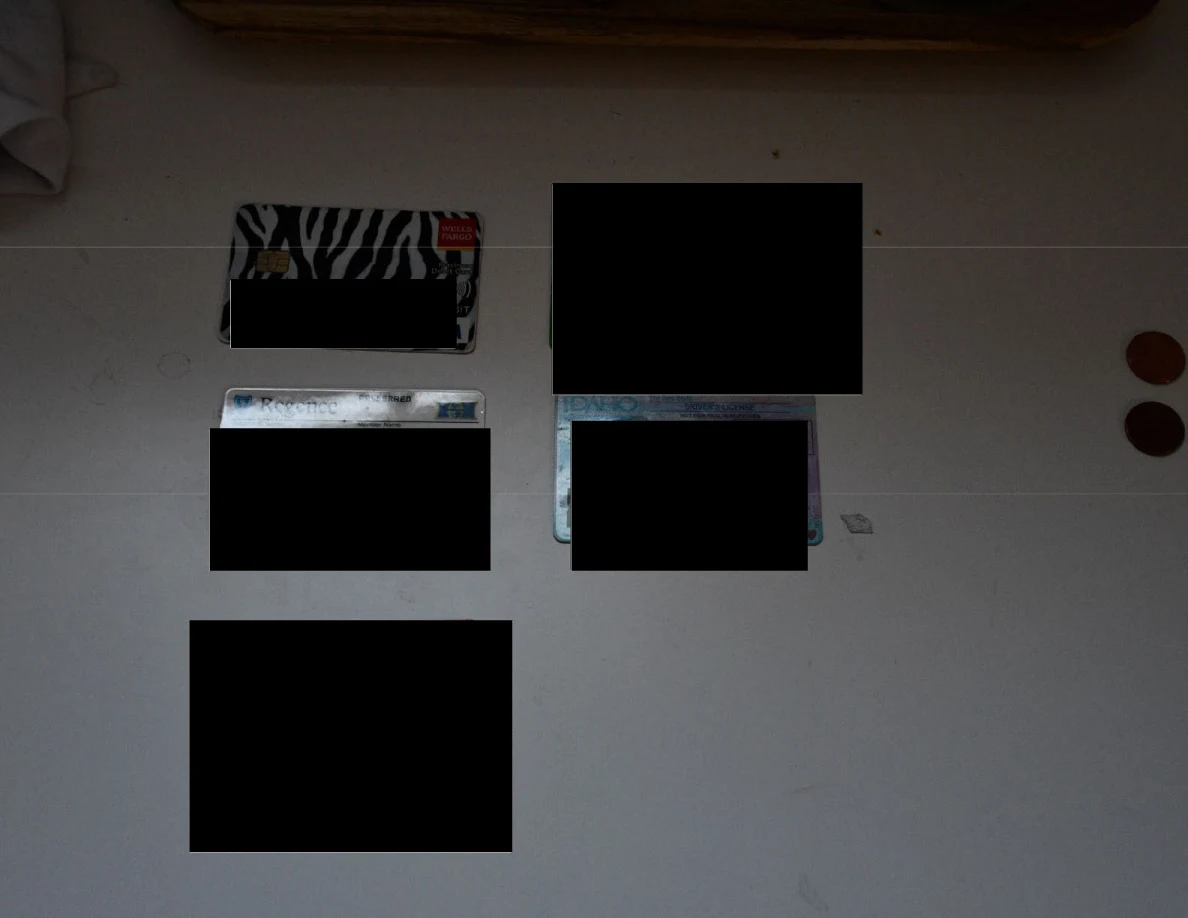 Several partly redacted cards laid out on a white surface beside two coins.