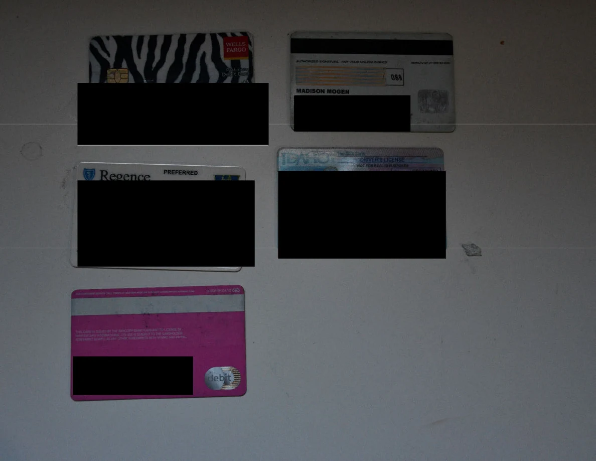 Bank, identification and insurance cards arranged on a white surface with personal details redacted.