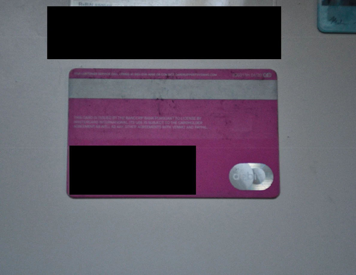 Reverse side of a pink payment card with identifying details redacted.