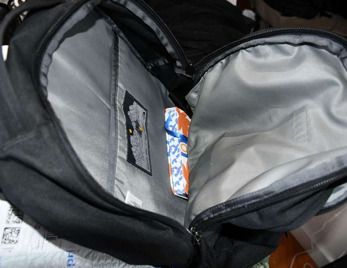 Wider view inside an open backpack with a colorful package in its compartment.