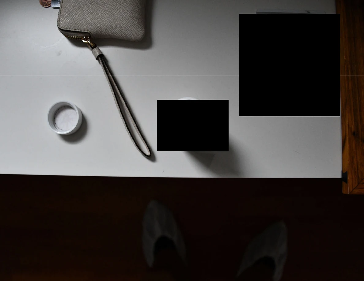 White surface holding a wristlet, loose bottle cap and redacted items.