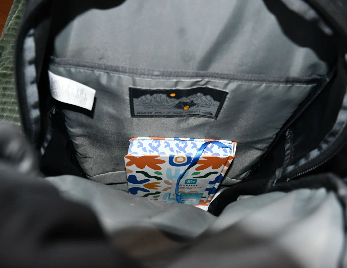Gray-lined backpack interior with a colorful package in a compartment.