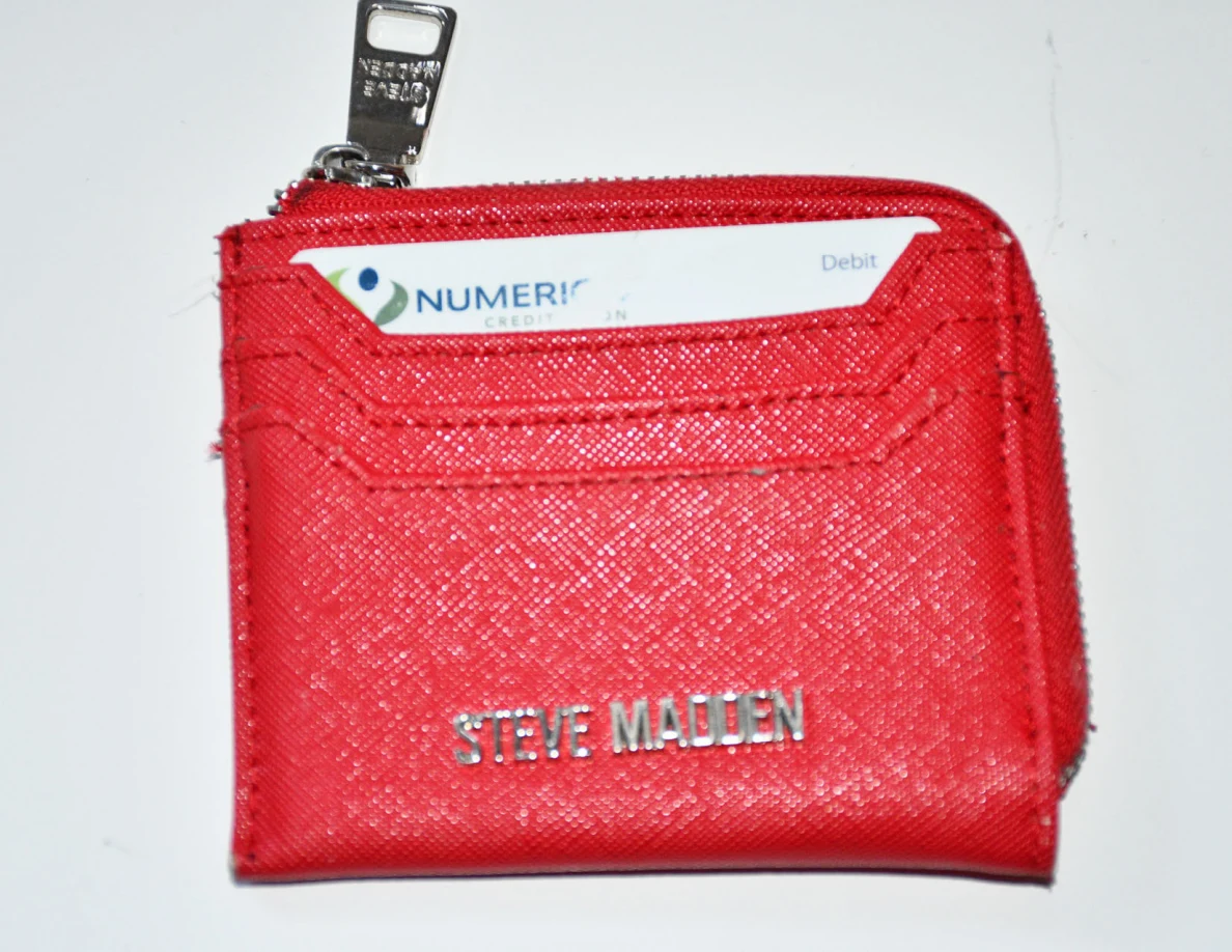 Close view of a red zippered card wallet with a bank card partly visible.