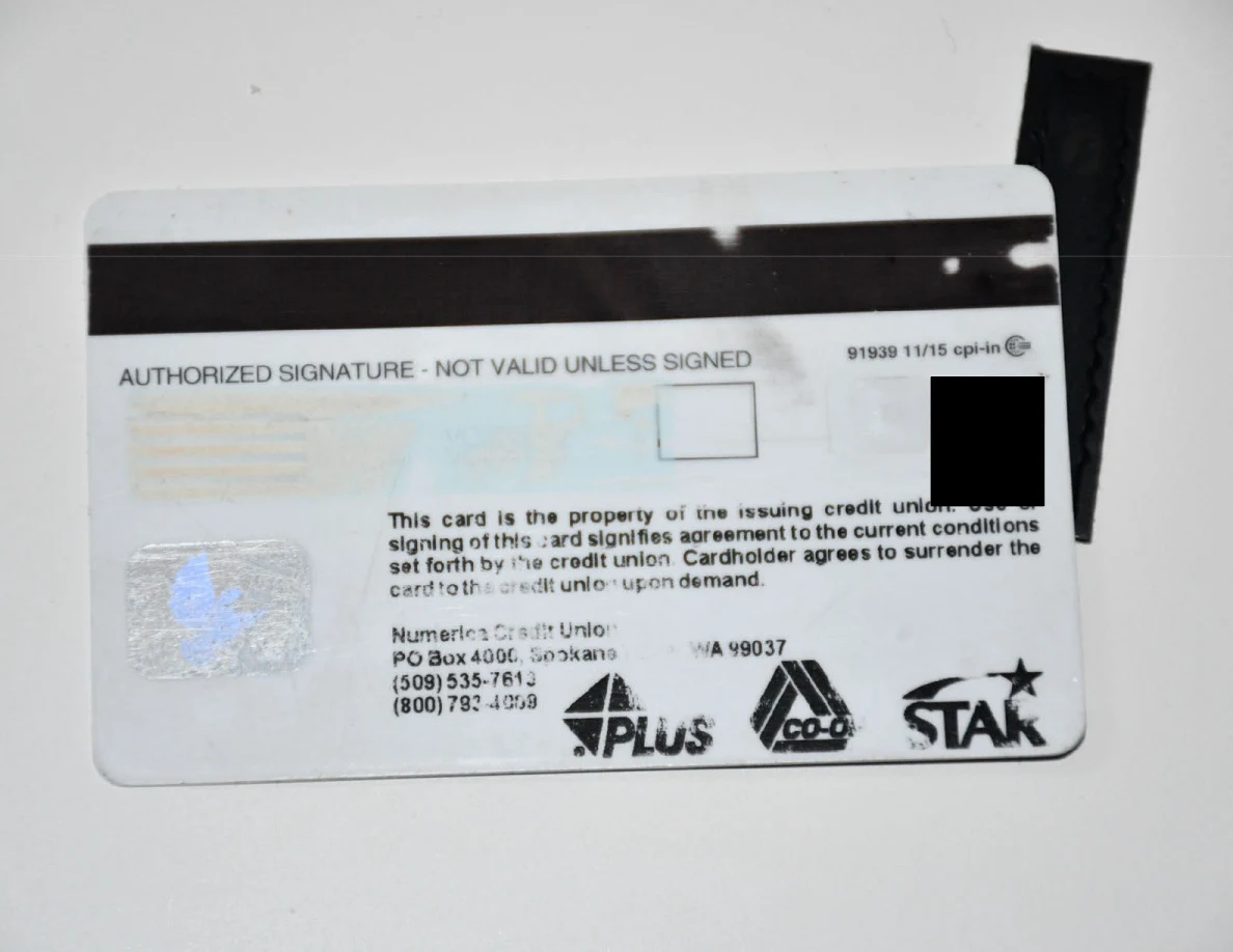 Reverse of a bank card beside a strip of black tape.