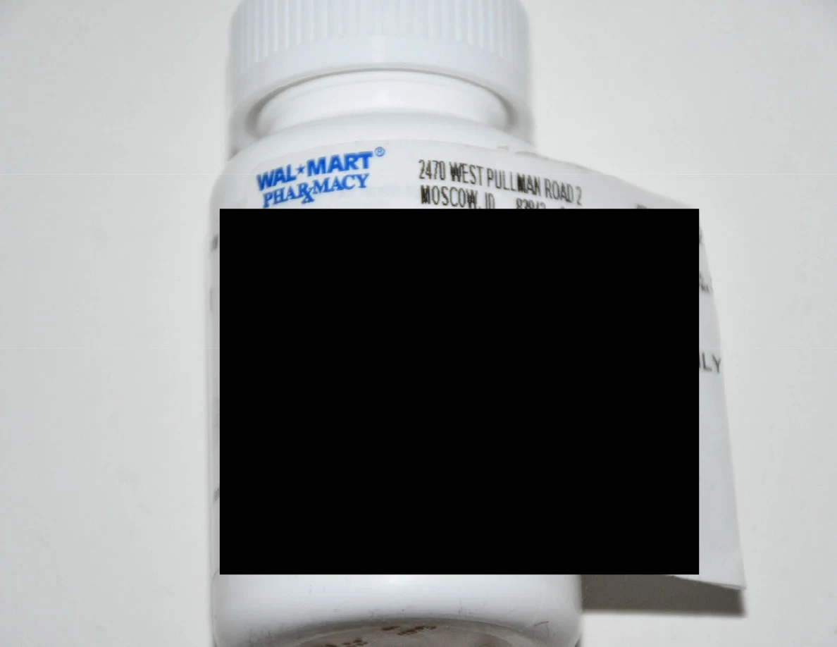 White prescription bottle with its label largely obscured by a black redaction.