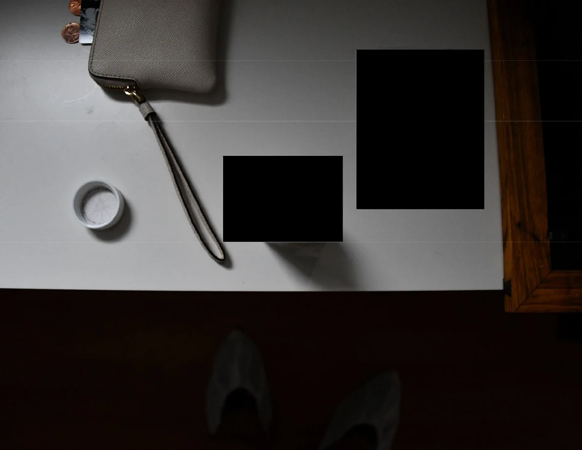 Overhead view of a wristlet strap, bottle cap and redacted items.