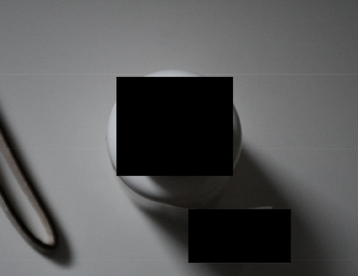 Small round container on a pale surface largely covered by a black redaction.