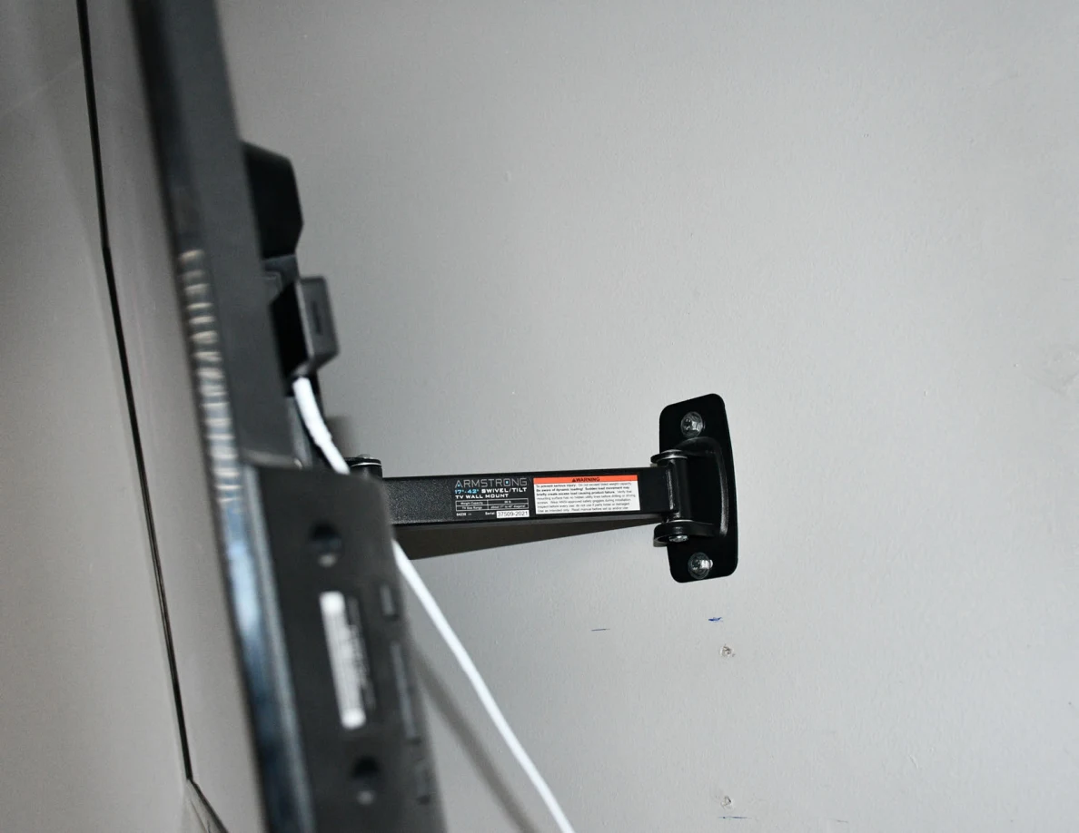 Side of a television on an articulated wall bracket with connected cable.