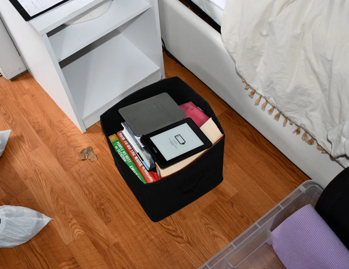 Black book bin on the floor with an e-reader in an open cover.