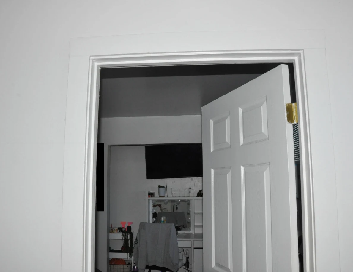 Upper doorway trim and open door facing a bedroom television and vanity.