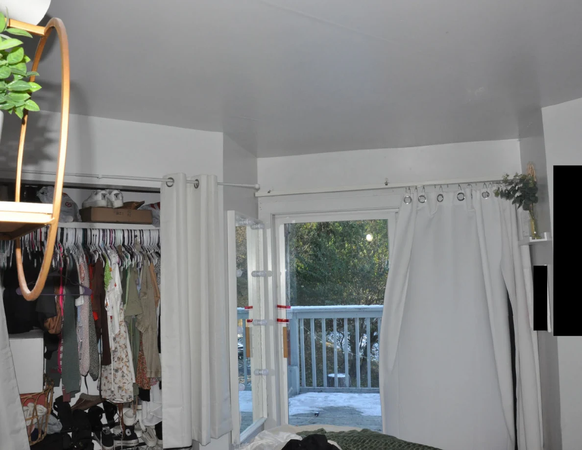 Open closet and curtains beside an open glass door leading onto a balcony.