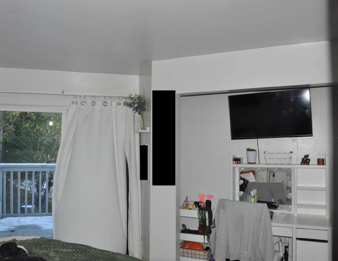 Bedroom wall with television and vanity beside the open balcony doorway.