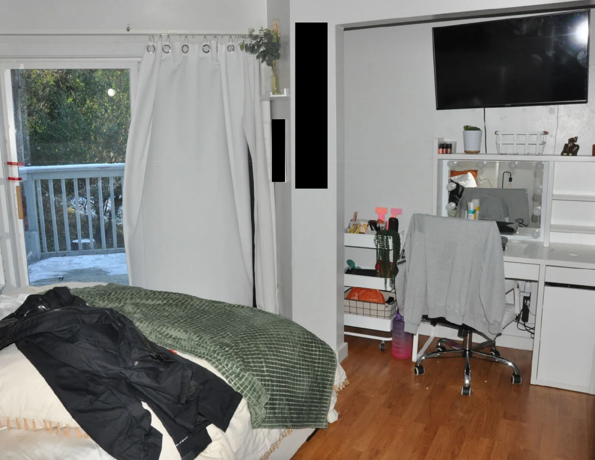 Bed, rolling chair and vanity beside an open balcony door.