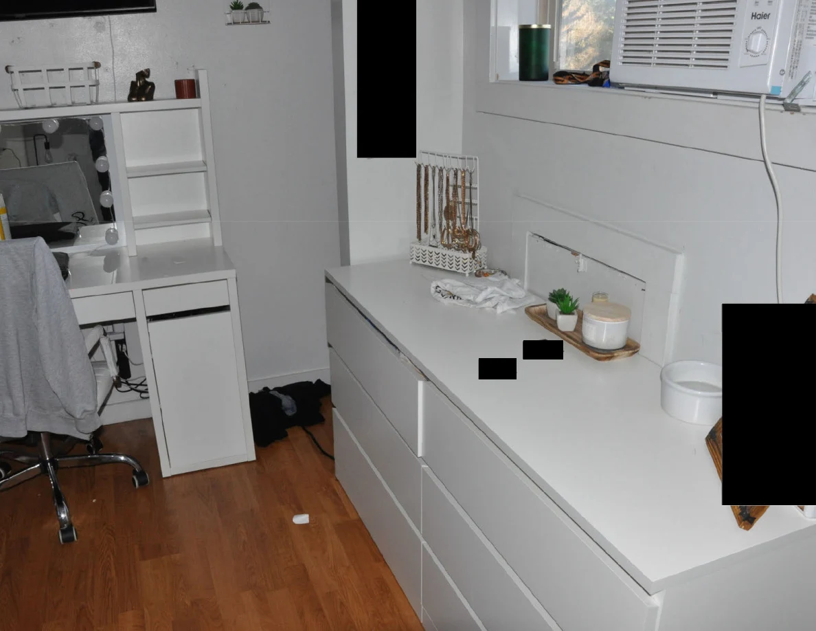 White dresser and vanity beneath a window air conditioner, with jewelry and small objects.