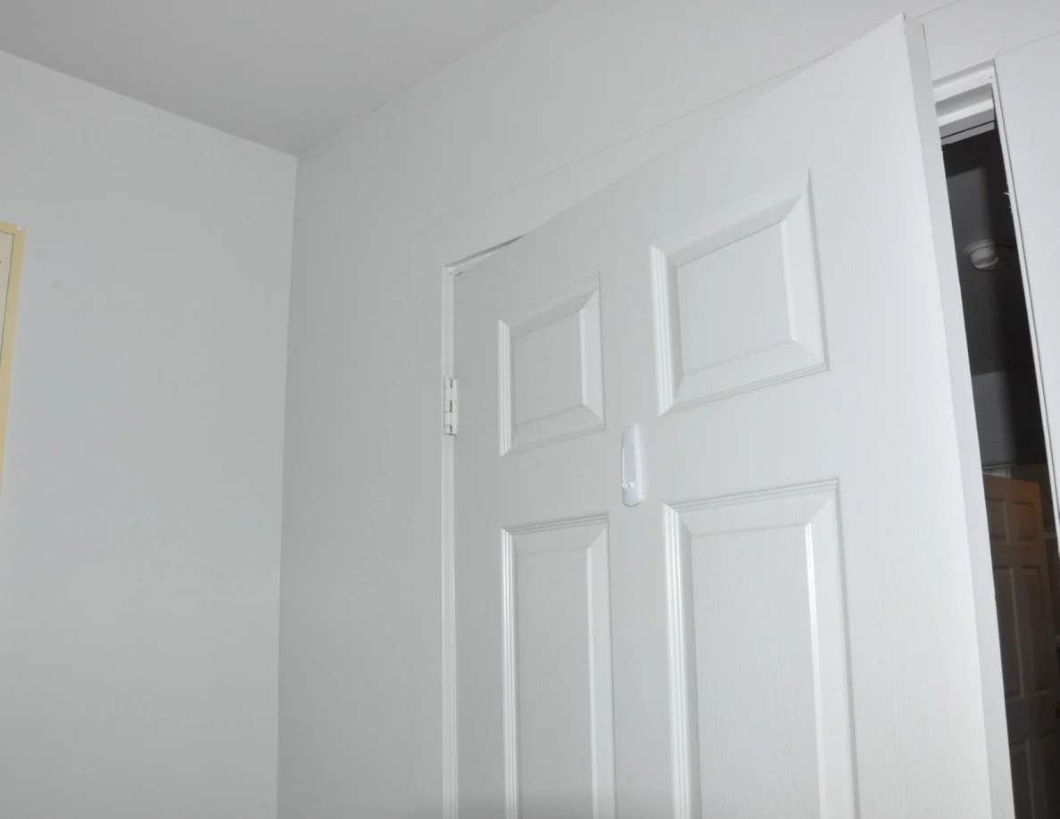 Upper white paneled door and ceiling corner with a small hanging tag.