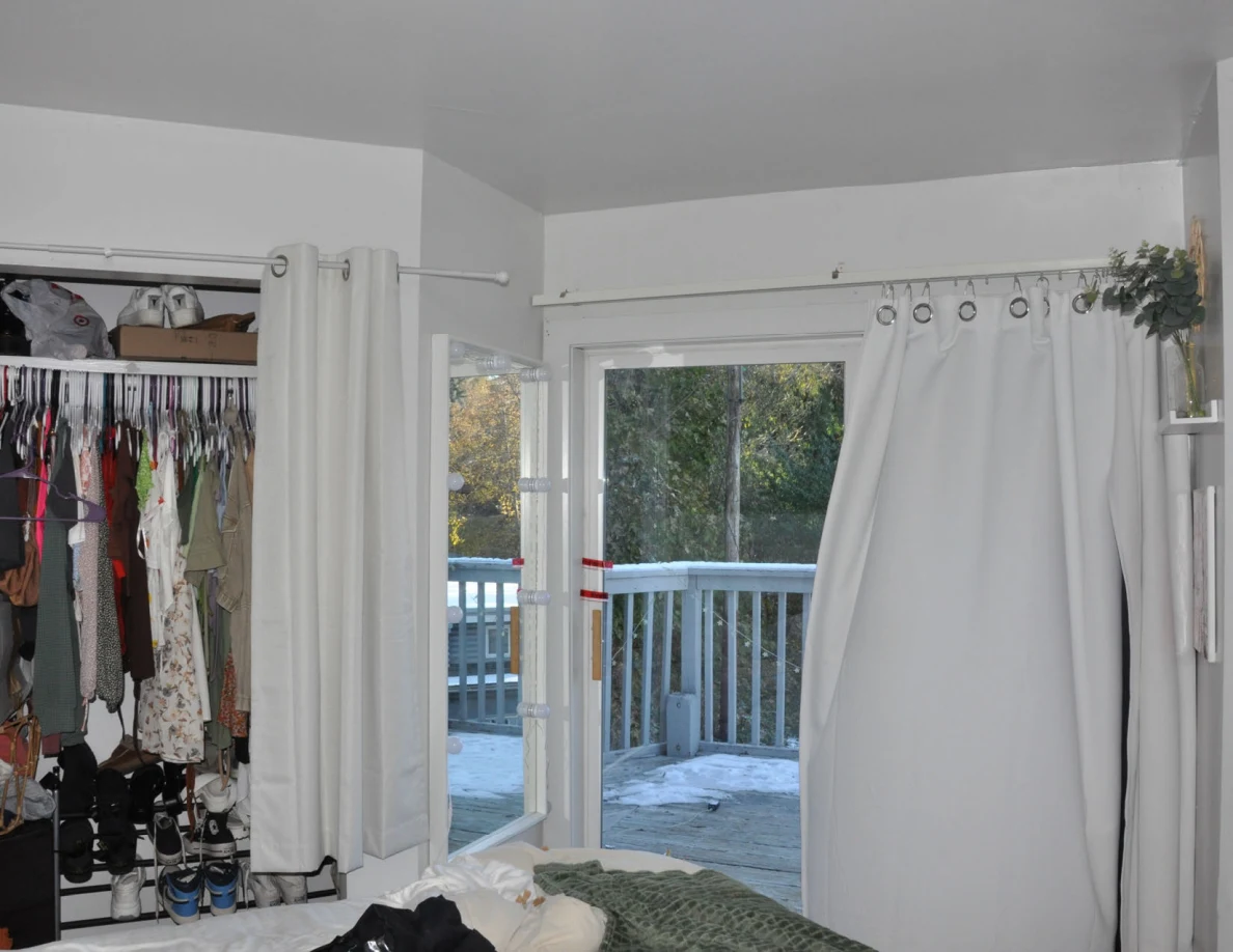 Upper balcony doorway beside white curtains and an open closet.