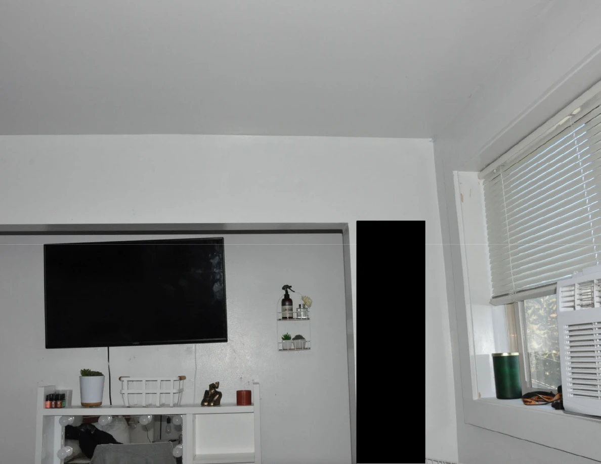 Upper television and vanity area beside window blinds.