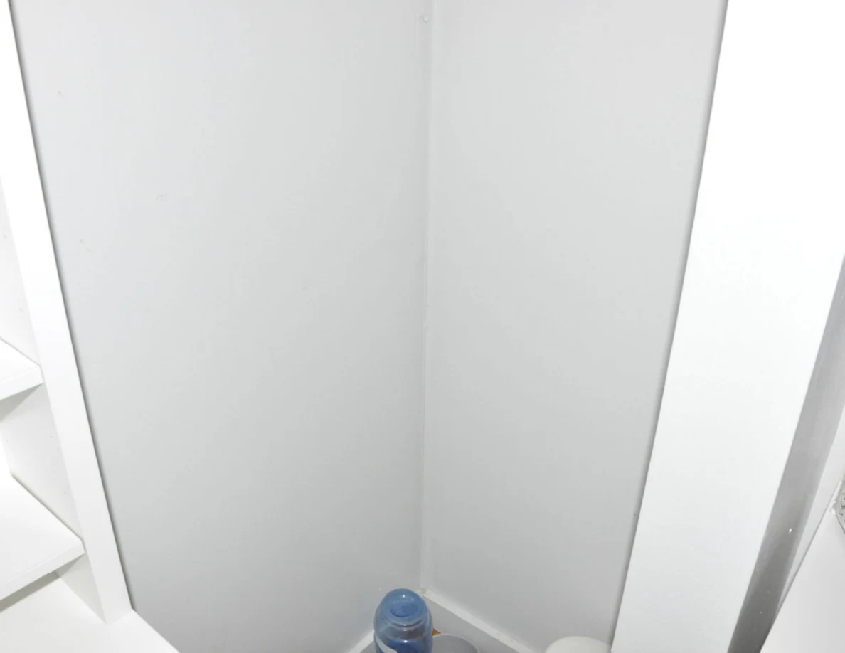Plain wall recess between white furniture above a partly visible pet water dispenser.