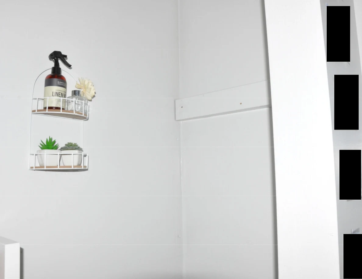 Two small wall baskets holding a spray bottle, decorative flower and small plants.