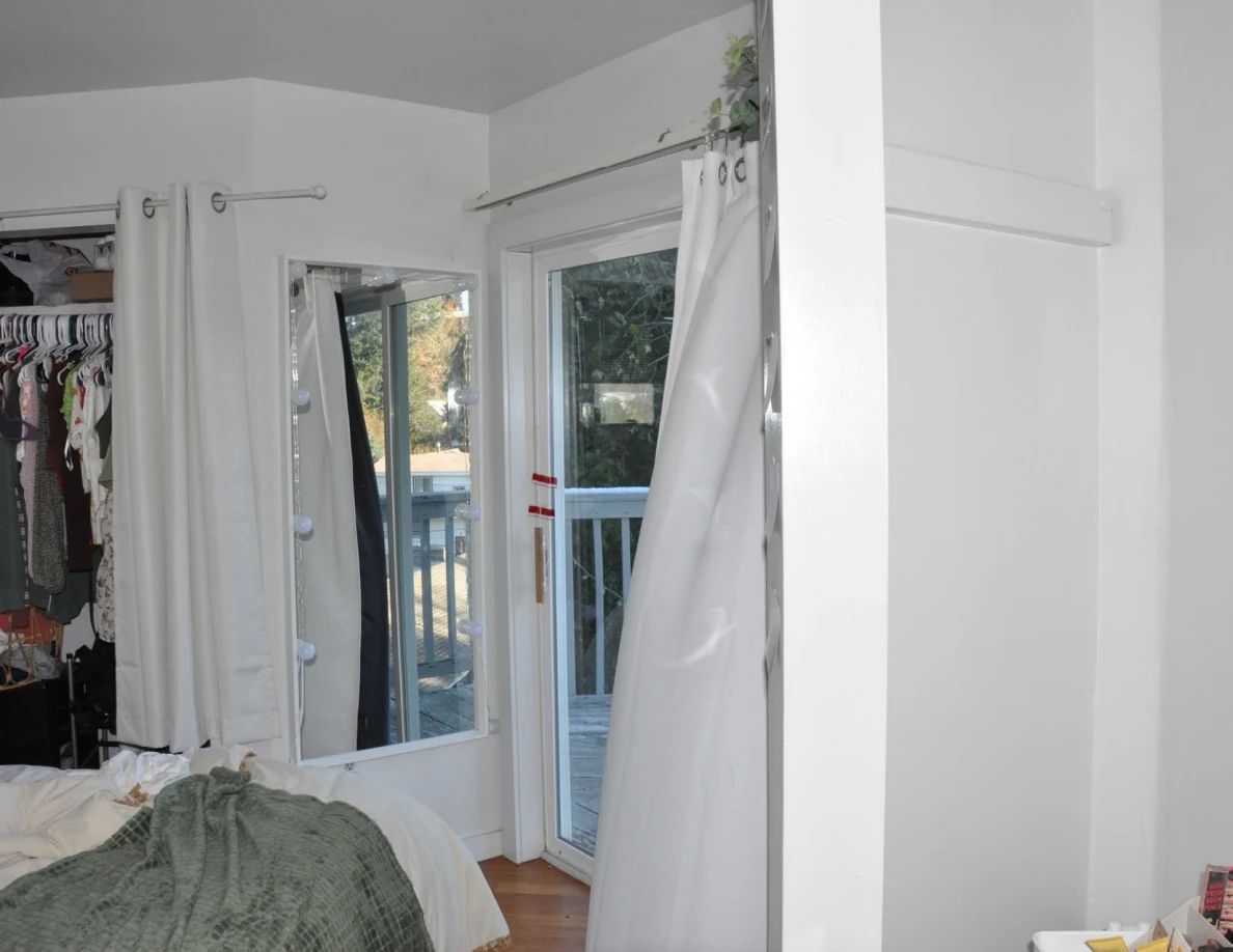 Upper open balcony door and mirrored panel beside curtains and a closet.