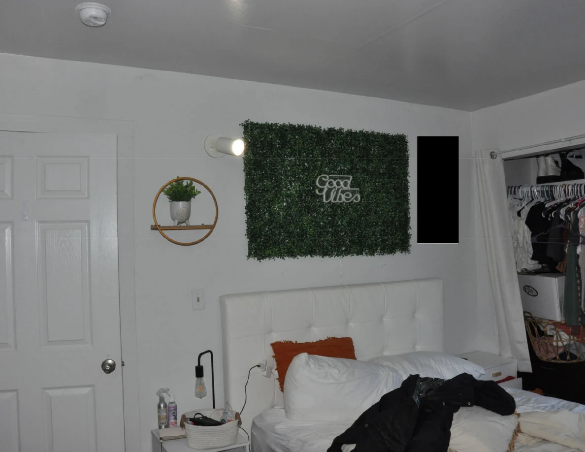 Upper bedroom view of a greenery panel, wall planter and closed door above a bed.