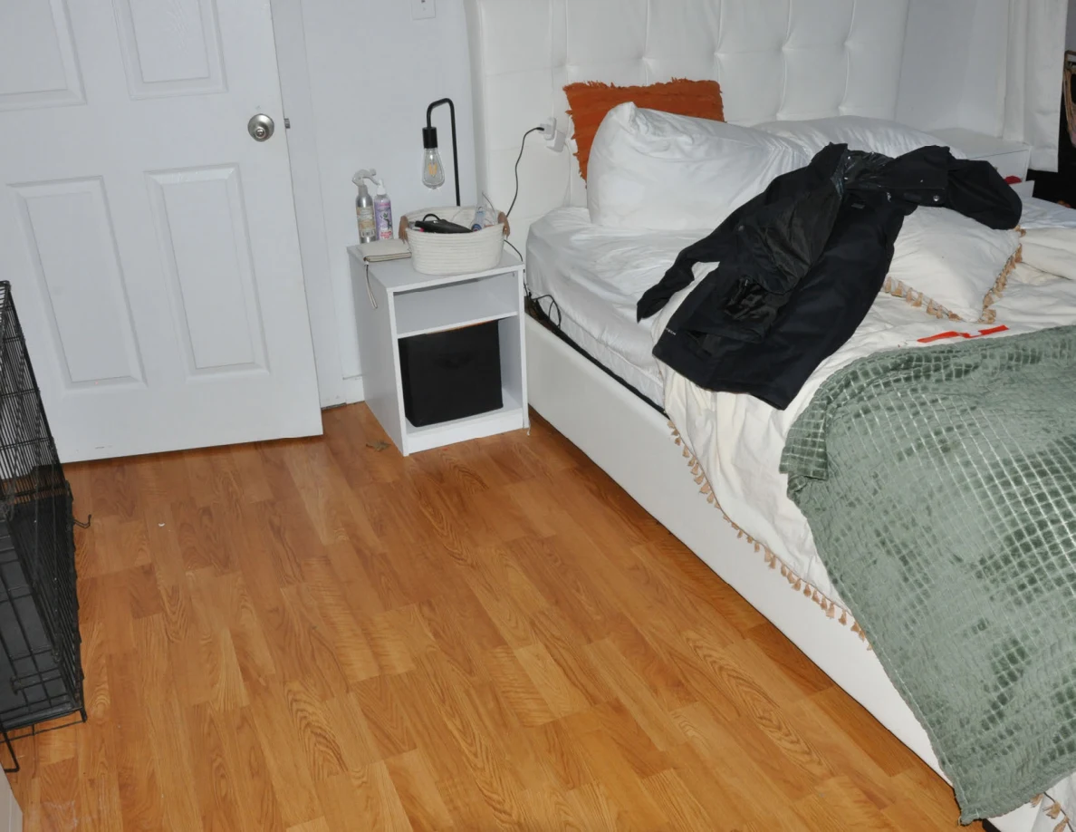 Bedside shelf and bed with dark clothing beside a closed white door.