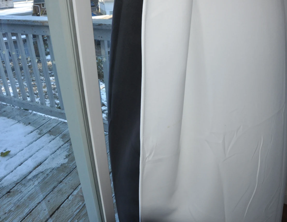White curtain beside glass door overlooking a snowy balcony.