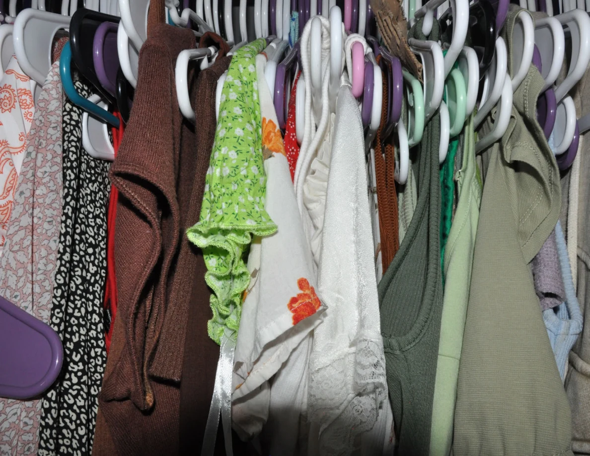 Closet clothes on closely packed multicolored hangers.