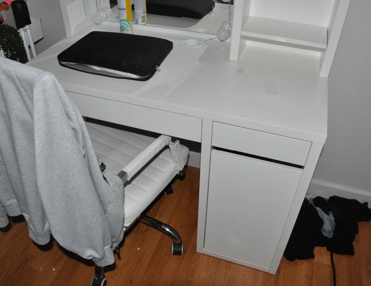 White vanity and chair draped in gray fabric, with a black case on the tabletop.