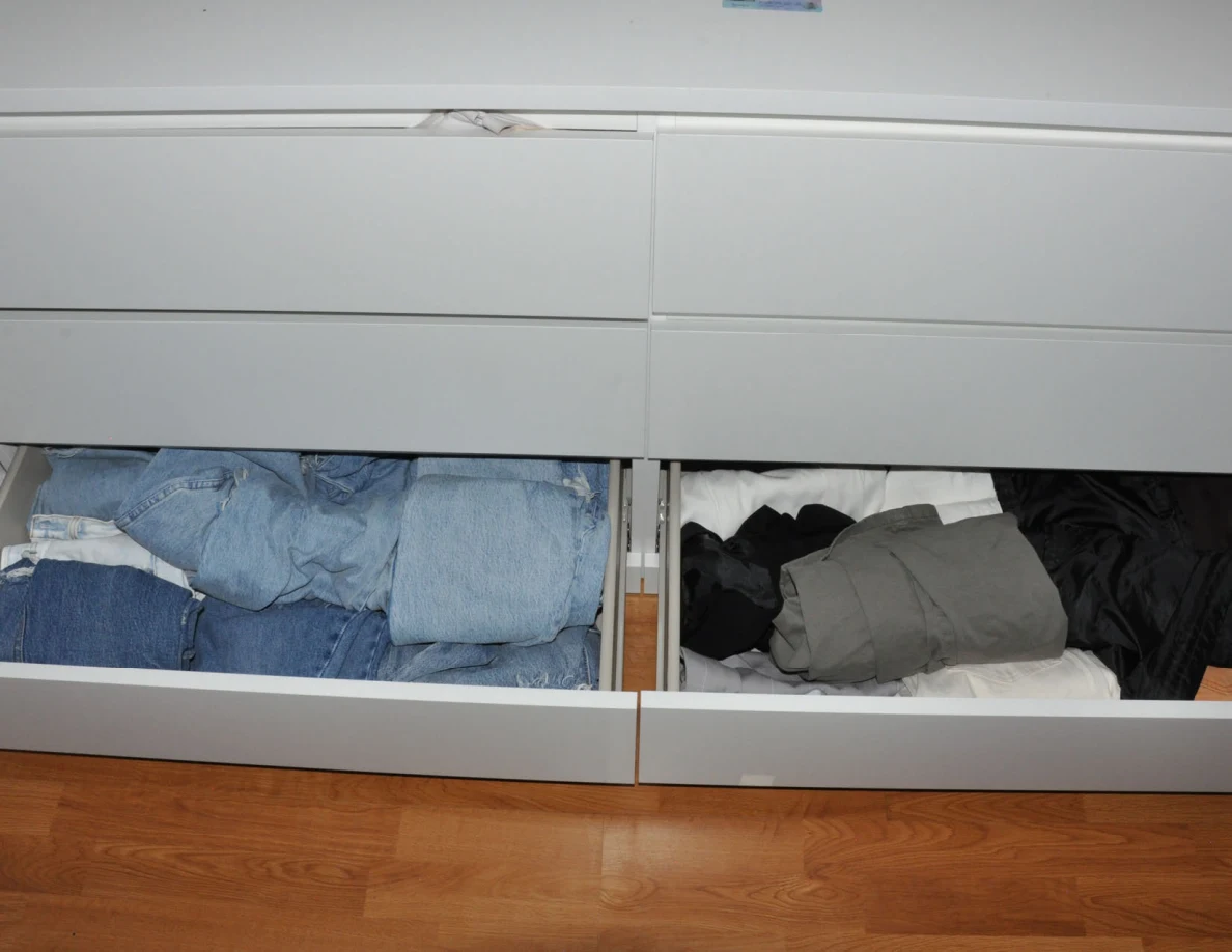Two lower dresser drawers open to reveal folded jeans and other clothing.