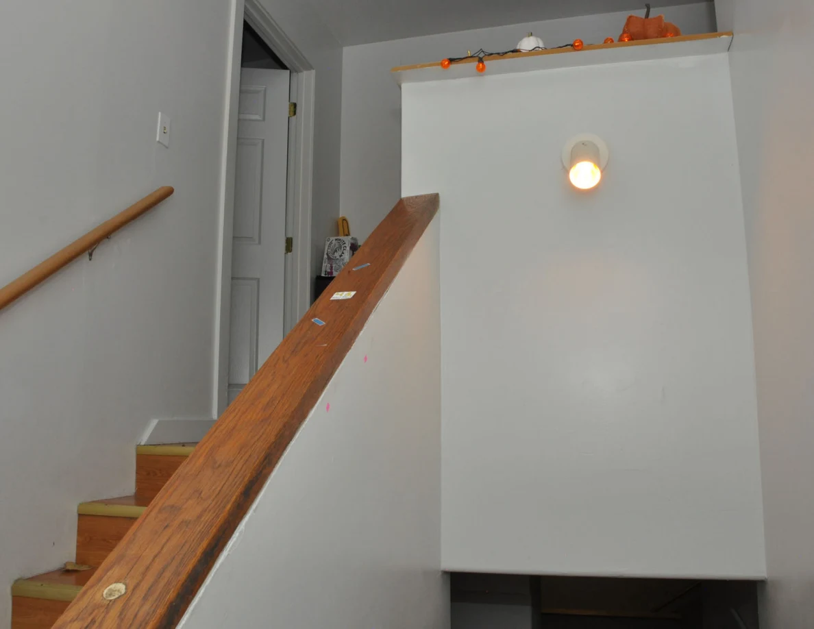 Stairwell half-wall with a wooden cap, lit fixture and small decorations along the top.