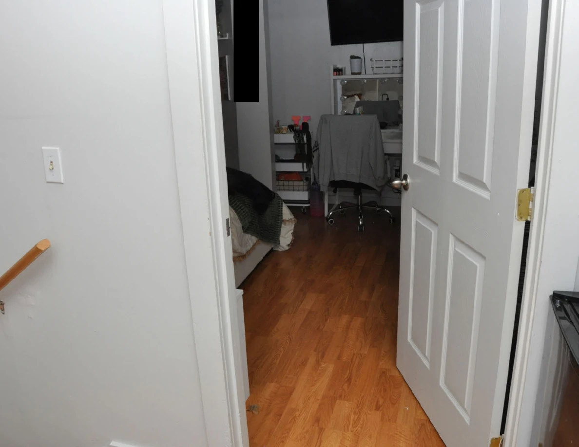 Angled view through an open bedroom door toward a vanity and television.