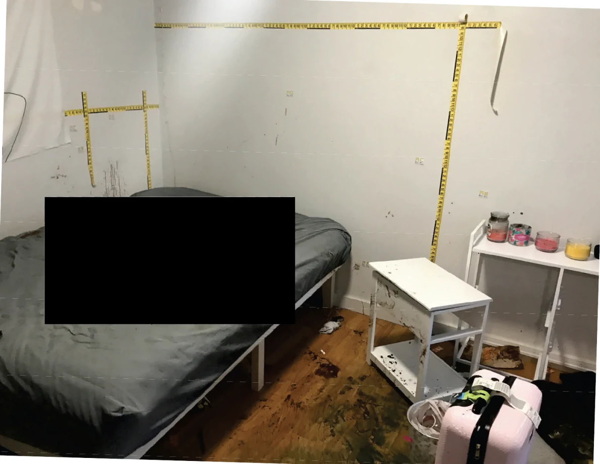 Bed and white bedside furniture below yellow measurement tape, with a large redaction over the bed.