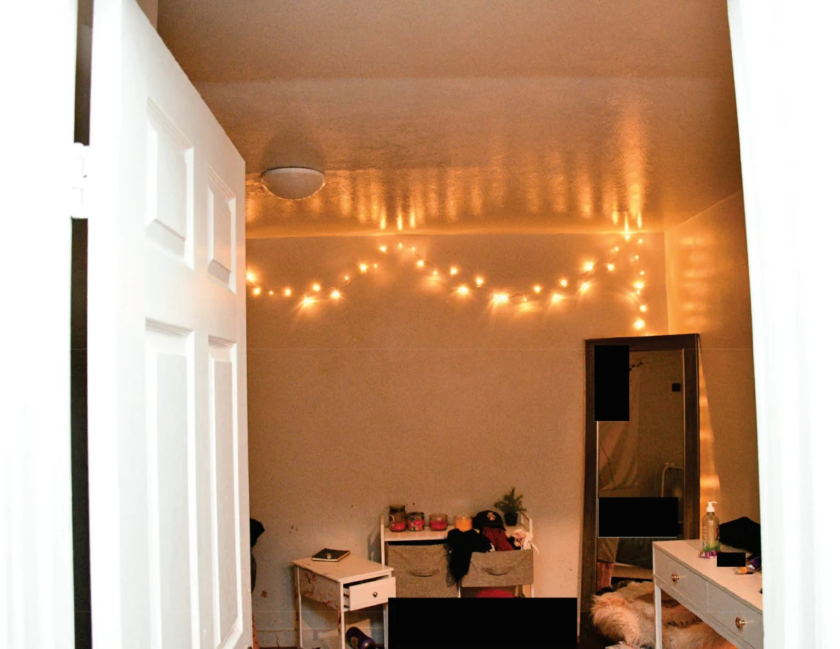Upper bedroom walls and ceiling with glowing string lights and a tall mirror.
