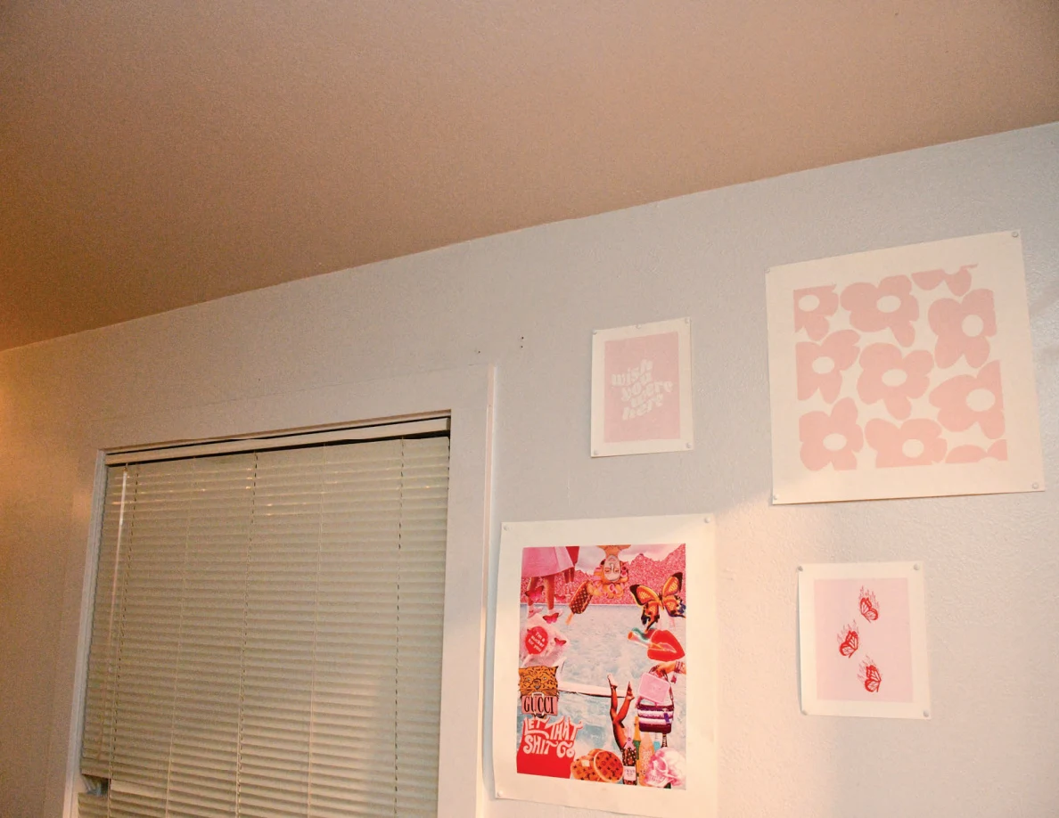 Upper bedroom wall with pink prints and collage beside a window.