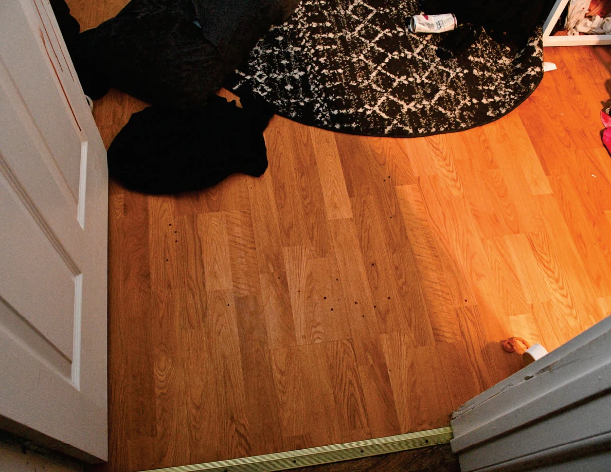 Bedroom doorway floor with dark clothing and a patterned round rug.