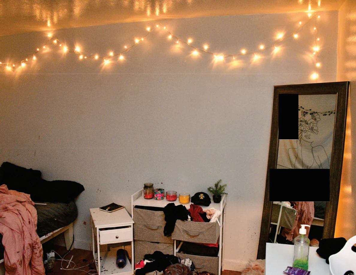 String lights above a bed edge, bedside furniture and tall mirror with redacted areas.